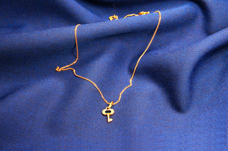 key pendant on a dark blue velvet backgroundの写真素材