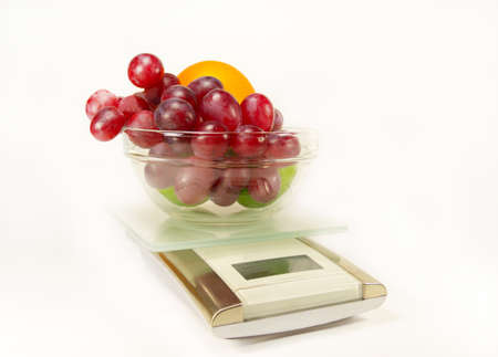 Scales with grapes, lime and orange isolatedの写真素材