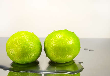 Two lime in water drops on mirror surfaceの写真素材