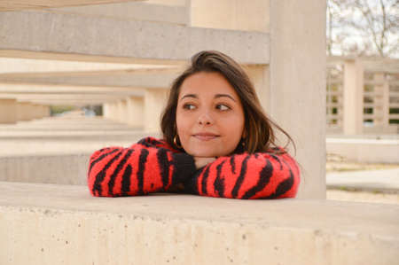 Young brunette girl smiling waiting outdoor with red and black clothesの写真素材