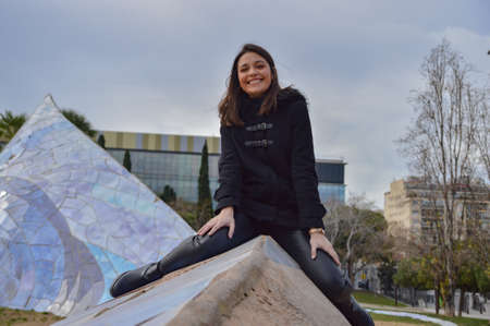 Young brunette girl smiling with black clothes in a parck of Barcelonaの写真素材