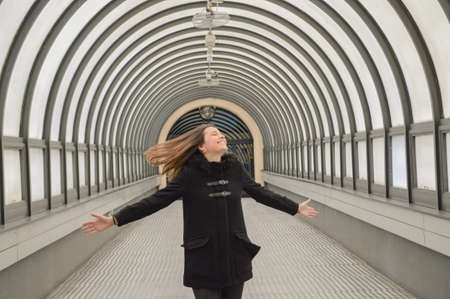 Young brunette girl smiling and dancing with black clothes and moving hairの写真素材