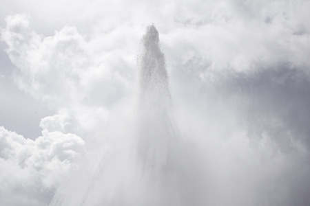 Urban water jet fountain with cloudy skyの写真素材