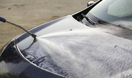 Washing car with hose and soap, mechanical workshop, vehicle maintenance
