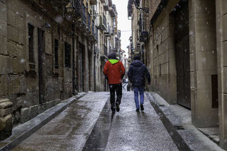Detail of two people under the snow in an old medieval town in Spainの写真素材