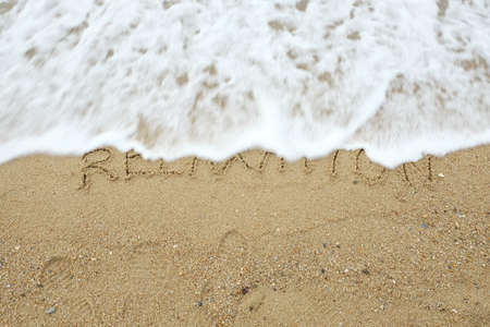 Relaxation concept. The word Relaxation written on sand being washed away by waveの写真素材