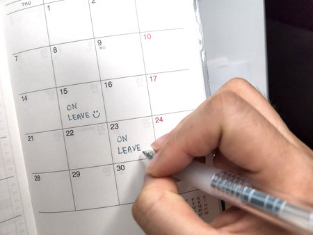 Close-up Of A Person's Hand Writing On Calendar With Penの写真素材