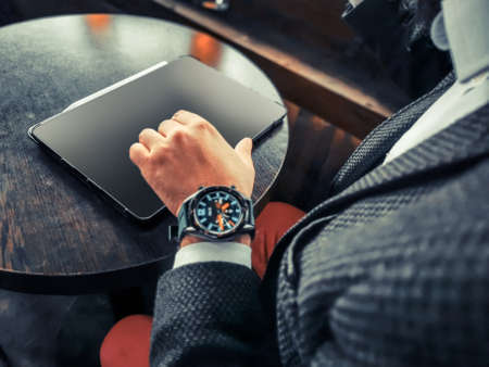 young adult businessman with tablet pro and smart watch checking the market stock exchange forex cryptocurrency in the cafe pubの写真素材