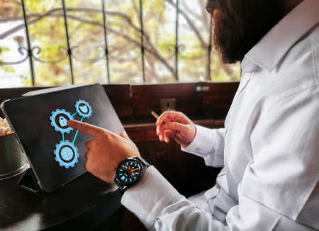 young adult with beard smart watch and cigar touching lock icon on his pro tabletの写真素材