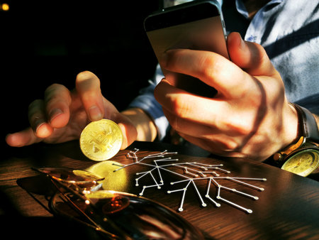 bitcoin holding rich male using his phone for remote exchange e-commerce e-business on the pub tableの写真素材
