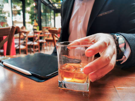 business man with beard who has smart watch using pro tablet and pencil interacting with tablet screen holographic economy floating graphics data drinking whiskey in the cafe pubの写真素材