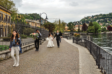 Como, Italy - May 06, 2013. View of newlyweds strolling along the promenade of Como Lake. Near the city of Como, a pleasant town a few miles from Milan. Located in the Lombardy region, northern Italyのeditorial素材