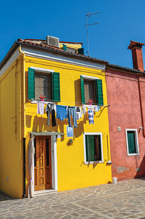 Burano, Italy - May 08, 2013. View of colorful terraced houses and clothes hanging in an alley on sunny day in Burano, a gracious little town full of canals, near Venice. Veneto region, northern Italyのeditorial素材