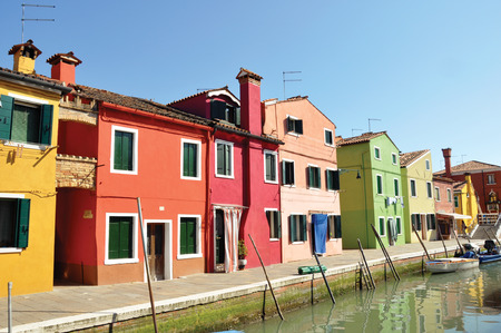 Panoramic view of colorful buildings and boats in front of the canal, in a sunny day at Burano, a gracious little town full of canals, near Venice. Located in the Veneto region, northern Italyの写真素材
