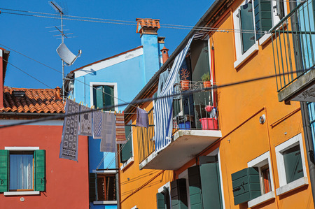 View of colorful terraced houses, balcony and clothes hanging in an alley on sunny day in Burano, a gracious little town full of canals, near Venice. Located in the Veneto region, northern Italyの写真素材