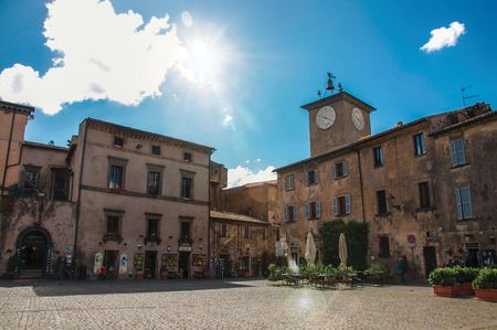 Orvieto, Italy - May 17, 2013. Square with old buildings, clock tower, shop and sunny sky in Orvieto, a pleasant and well preserved medieval town. Located in Umbria, central Italy. Retouched photoのeditorial素材