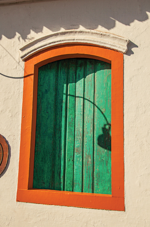 Close-up of colorful wooden window with closed green blinds in Paraty, an amazing and historic town totally preserved in the coast of Rio de Janeiro State, southwestern Brazilの写真素材