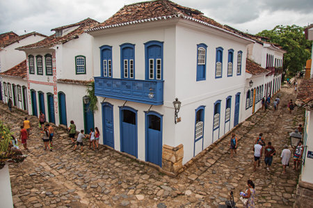 Paraty, Brazil - January 23, 2015. View of people in alley with stone sidewalk and old houses on cloudy day in Paraty, an amazing and historic town totally preserved in Rio de Janeiro State coastのeditorial素材