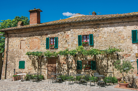 Facade view of an old house with creepers in the hamlet of Monteriggioni. A medieval fortress, surrounded by stone walls, at the top of a hill, near Siena. Located in the Tuscany regionのeditorial素材