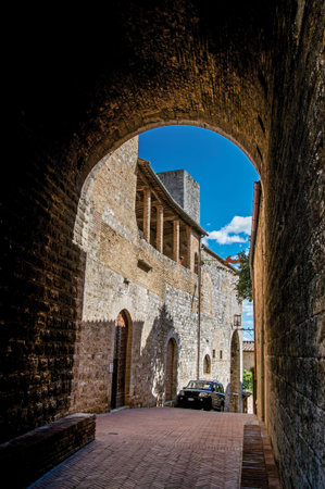 San Gimignano, Italy - May 13, 2013. View of dark alleyway, brick building and tower in San Gimignano. A medieval town famous for having several towers in its historical center. Tuscany regionのeditorial素材