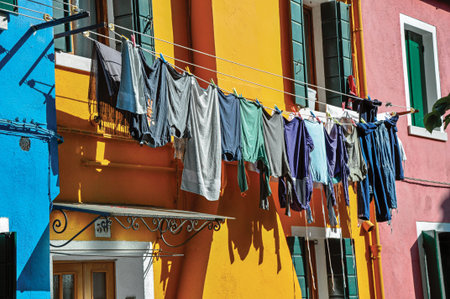 Burano, Italy - May 08, 2013. Close up of windows on colorful walls and clothes hanging on sunny day in Burano, a gracious little town full of canals, near Venice. Veneto region, northern Italyのeditorial素材