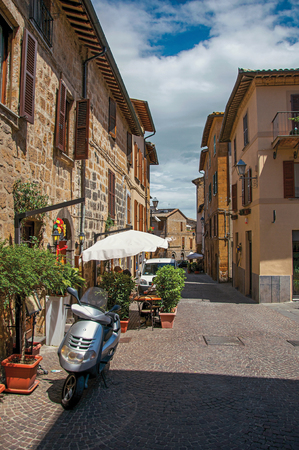 Orvieto, Italy - May 17, 2013. Overview of an alley with old buildings and scooter under a sunny blue sky, at the town of Orvieto, a pleasant and well preserved medieval city. Located in Umbriaのeditorial素材