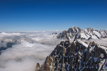 Snowy peaks and mountains in a sunny day, viewed from the Aiguille du Midi, near Chamonix. A famous ski resort located in Haute-Savoie Province, at the foot of Mont Blanc in the French Alps.の写真素材