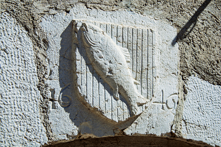 Heraldic shield carved in stone with fish and date in the historical city center of Annecy. Located in the department of Haute-Savoie, Auvergne-Rhone-Alpes region, south-eastern France.の写真素材