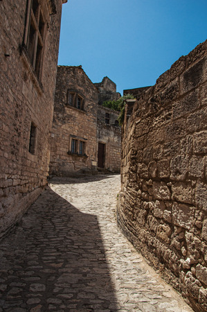 View of traditional stone houses on an alley of the historical city center of Baux-de-Provence, under sunny blue sky. Bouches-du-Rhone department, Provence-Alpes-Côte d'Azur region, southeastern Franceの写真素材