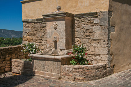 View of stone fountain with flowers and sunny blue sky, in the village of Menerbes. Located in the Vaucluse department, Provence-Alpes-Côte d'Azur region, southeastern Franceの写真素材