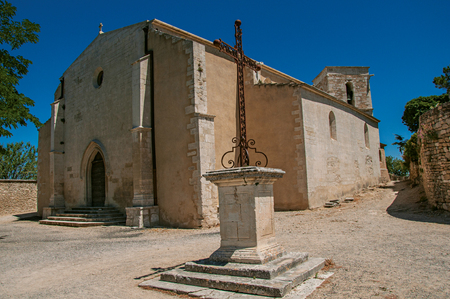 Menerbes, France - July 07, 2016. Front facade of stone church on a sunny day with foreground cruise, in the historical village of Menerbes. Vaucluse department, Provence region, southeastern Franceのeditorial素材