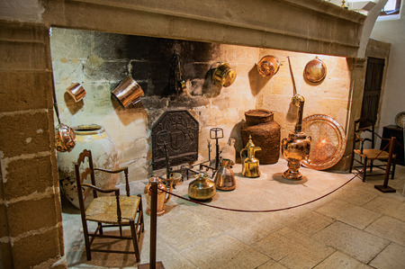 Lourmarin, France - July 07, 2016. Large stone fireplace with decorative copper kitchenware and chairs in Lourmarin castle. Vaucluse department, Provence-Alpes-C?te d'Azur region, southeastern Franceのeditorial素材