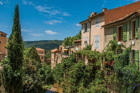 View of houses near creek and bluff with vegetation in the charming village of Moustiers-Sainte-Marie. In the Alpes-de-Haute-Provence department, Provence region, southeastern Franceの写真素材