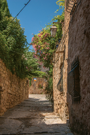 View of stone houses in a narrow alley under blue sky, at the gorgeous medieval hamlet of Les Arcs-sur-Argens, near Draguignan. Located in the Provence region, Var department, southeastern Franceの写真素材