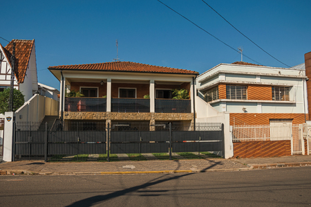 San Manuel, southeast Brazil - October 14, 2017. Modern townhouse with garage door and balcony in an empty street on a sunny day at San Manuel. A cute little town in the countryside of São Paulo Stateのeditorial素材