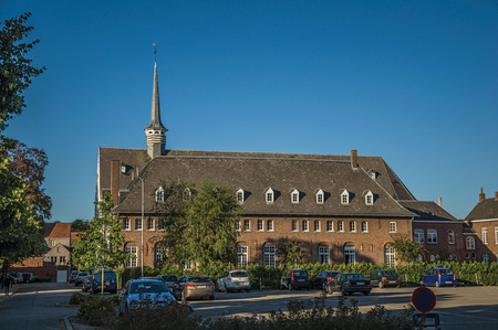 Tielt, Belgium - July 02, 2017. Brick building and parking lot at sunset in Tielt. Charming and quiet village in the countryside, near Ghent and surrounded by agricultural fields. Western Belgium.のeditorial素材
