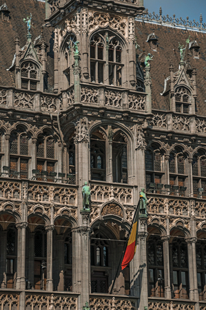 Richly decorated facade in Gothic style of Brussels City Museum and Belgian flag, at Grand Place. Vibrant and friendly, is the country's capital and administrative center of the EU. Central Belgiumのeditorial素材