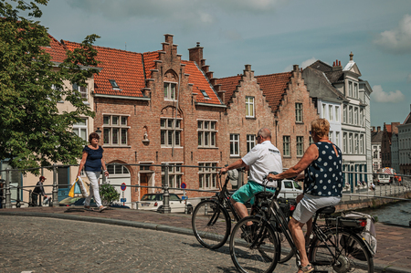 Bruges, Belgium - July 05, 2017. Cyclists and walker on bridge over canal in Bruges. With many canals and old buildings, this graceful town is a World Heritage Site of Unesco. Northwestern Belgium.のeditorial素材