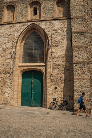 Bruges, Belgium - July 05, 2017. Wooden gate on Gothic church and man in Bruges. With many canals and old buildings . Northwestern Belgium.のeditorial素材