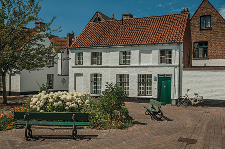 Bruges, Belgium - July 05, 2017. Facade of brick houses around flowerd little square with tree at Bruges. With many canals and old buildings, this graceful town is a World Heritage Site of Unesco.のeditorial素材