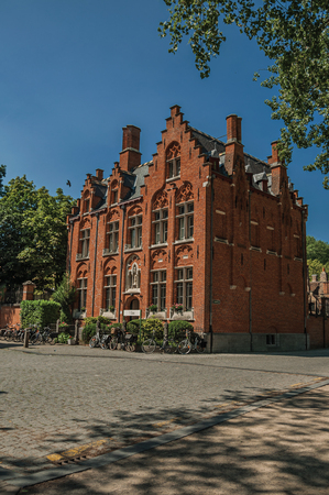 Bruges, northwestern Belgium - July 05, 2017. Brick facade of old house, trees and bicycles in Bruges. With many canals and old buildings, this graceful town is a World Heritage Site of Unesco.のeditorial素材