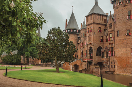 De Haar Castle with brick towers, water moat and lawn garden on rainy day, near Utrecht. Of medieval...