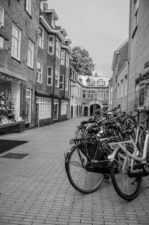 s-Hertogenbosch, southern Netherlands - July 01, 2017. Several bikes stopped at the alley entrance in the s-Hertogenbosch City Center. Historical city with huge cultural life. Black and white photo.のeditorial素材