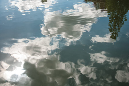 Clouds and tree reflected in canal water surface on sunny day in Weesp. Quiet and pleasant village...