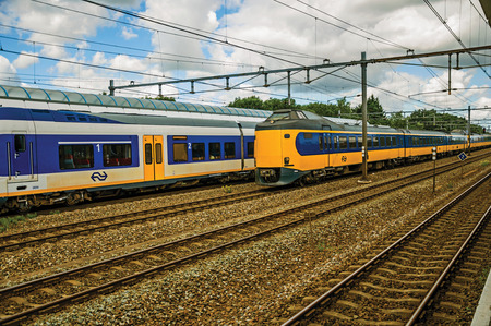 Weesp, northern Netherlands - June 26, 2017. Locomotive stop on train station and other train passing by in cloudy day at Weesp. Quiet and pleasant village full of canals and green near Amsterdam.のeditorial素材