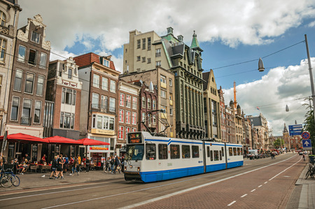Amsterdam, northern Netherlands - June 26, 2017. Street with tram, buildings and lots of people strolling in Amsterdam. The city is famous for its huge cultural activity, graceful canals and bridges.のeditorial素材