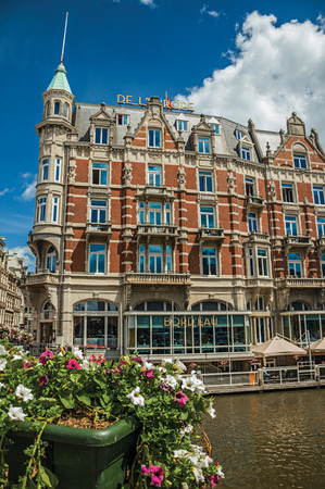 Amsterdam, northern Netherlands - June 26, 2017. Canal with typical brick building, restaurant, flowers and blue sky in Amsterdam. Famous for its huge cultural activity, graceful canals and bridges.のeditorial素材