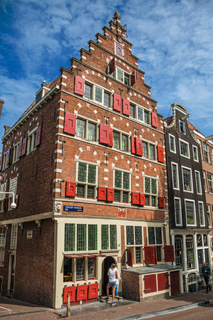 Amsterdam, northern Netherlands - June 27, 2017. Brick buildings facade and people under sunny blue sky in Amsterdam. The city is famous for its huge cultural activity, graceful canals and bridges.のeditorial素材