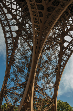 View of one leg's iron structure of the Eiffel Tower, with blue sky and sunshine in Paris. Known as the "City of Light", it is one of the most impressive cultural centers in the world. Northern France.の写真素材
