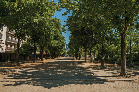 Paris, France - July 07, 2017. People walking on sidewalk with trees on a sunny day in Paris. Known as the "City of Light", it is one of the world's most awesome cultural centers. Northern France.のeditorial素材